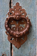 Ornate iron door knocker on mint green wooden door