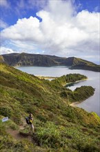 Hiker at the crater rim with view to the crater lake Lagoa do Fogo