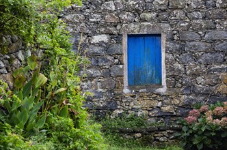 Residential house with stone facade and blue closed window in Rocha da Relva