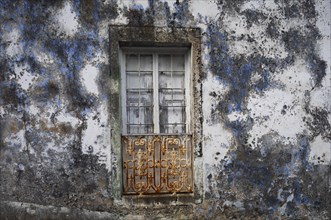 Weathered house facade with old closed window in Porto Formoso