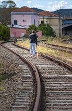 Young woman with dog walking on the disused railway bed in the town of Figari