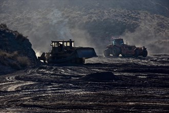 Bulldozers pushing hilly earth flat