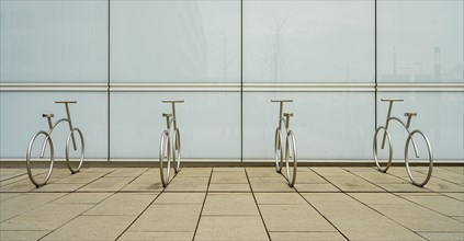 Design of aluminium bicycles in front of a bright plastic wall