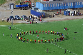 Footballers stand on grass pitch in the circle