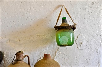 Clay jugs and broken wine bottle in front of white wall
