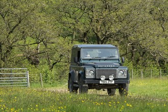 Farmer driving a Land Rover Defender over a field