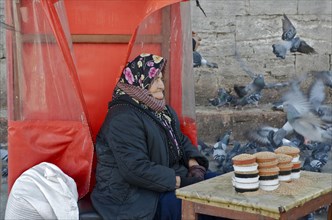 Old woman with headscarf selling flying pigeon food