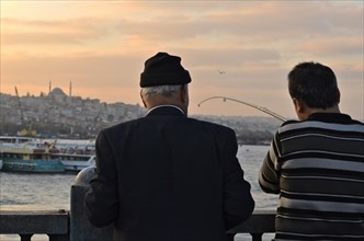 Anglers on Galata Bridge with a view of the Sueleymaniye Mosque at sunset