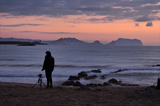Photographer with camera and tripod in the morning at the sea