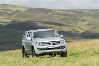 Four wheel drive VW Amarok twin cab pick up driving across upland pasture in North Yorkshire