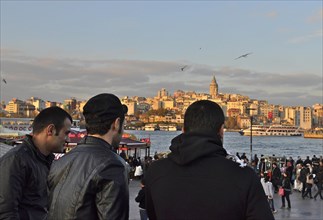 Young Turks on busy Golden Horn Square with Galata Tower