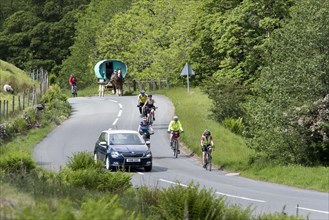 Vehicles overtaking on a busy rural road in Cumbria