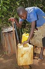 Rwandan girl filling container with fresh water from a tap