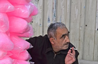 Smoking man sitting next to pink plastic bags