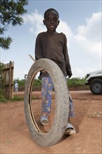 Children playing with a motorcycle tyre and a stick as a toy. Rwanda