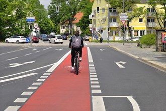 Cyclist on red bicycle lane between car lanes