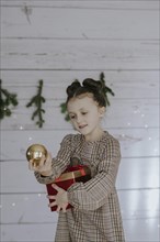 Girl with Christmas present in front of a Christmas backdrop