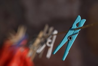 Turquoise plastic clothes peg on line with other pegs