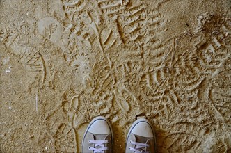 Sports shoes on dusty clay floor with footprints