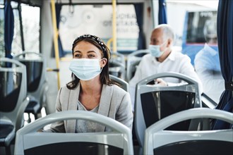 Young woman in protective mask traveling in the bus in Faro