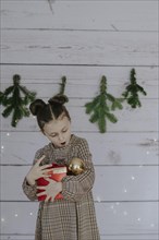 Girl with Christmas present in front of a Christmas backdrop