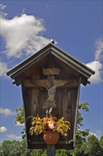 Wooden shrine with crucifix and flowerpot