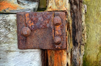 Rusty metal with rivets on old wood