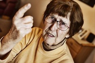Angry senior citizen threatens with her raised index finger