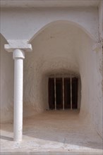 Round arch with column in front of barred window in cave house