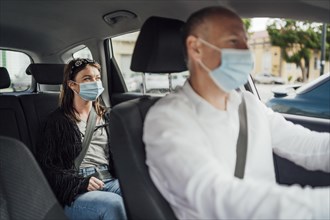Taxi driver in a mask with a female client on the back seat wearing mask