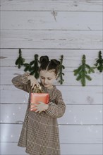 Girl with Christmas present in front of a Christmas backdrop