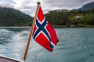The Norwegian flag flies at the stern of a boat on Lovatnet