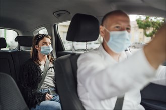 Taxi driver in a mask with a female client