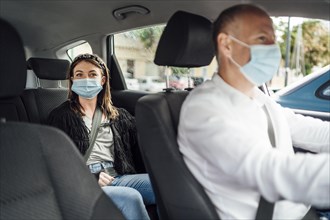 Taxi driver in a mask with a female client