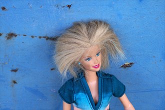 Barbie doll leaning against blue metal plate