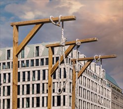 Symbolic gallows stand in front of the Brandenburg Gate during a protest rally