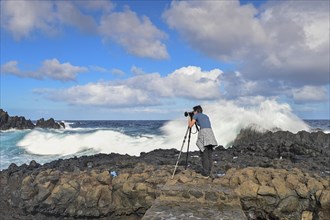 Photographer taking pictures in strong waves at the sea