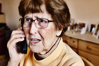 Senior citizen at home looking startled while phoning