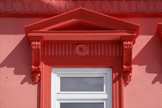 Ornate window on red house wall