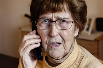 Senior citizen at home looking worried while phoning
