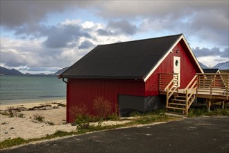 Red wooden cottage on the beach