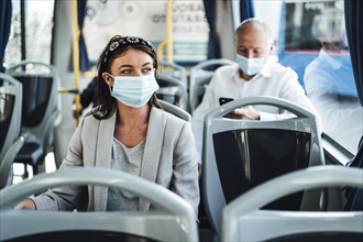 Young woman in protective mask traveling in the bus in Faro