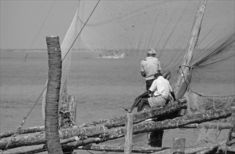 Fishermen with wooden net catching construction at the sea