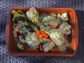 Cauliflower with carrots and gorgonzola sauce in clay dish