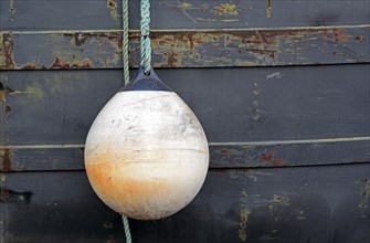 White ship's fender in front of old boat wall