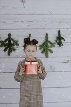 Girl with Christmas present in front of a Christmas backdrop