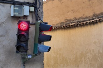 Two traffic lights on red at house wall