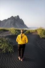 Young woman with rain jacket walks through dune