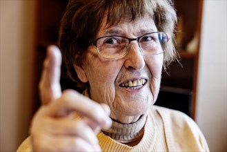 Senior citizen with raised forefinger at home in her living room
