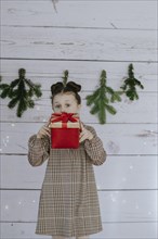 Girl with Christmas present in front of a Christmas backdrop